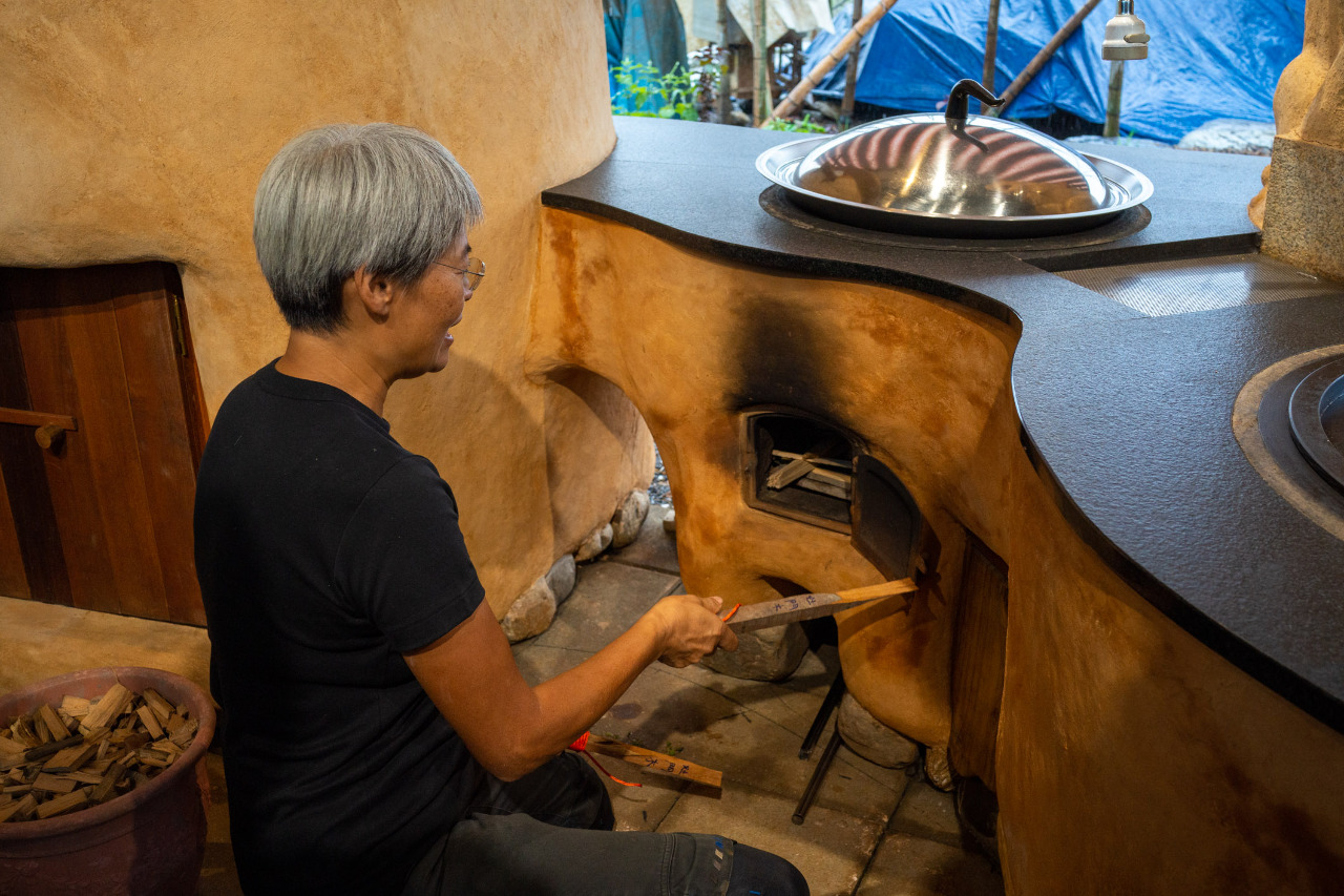 Emma Liao explique comment utiliser la cuisinière au feu de bois construite en terre crue © Sasa
