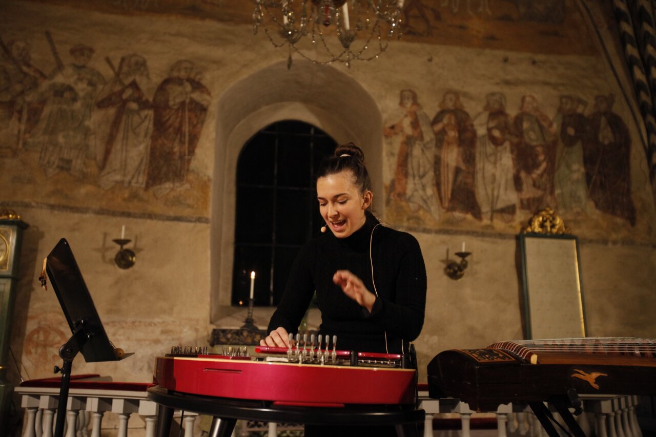 Barbora Xu chante et s'accompagne au Kantele, dans une église en Finlande (photo Tommi Tapiale, FB Barbora Xu)